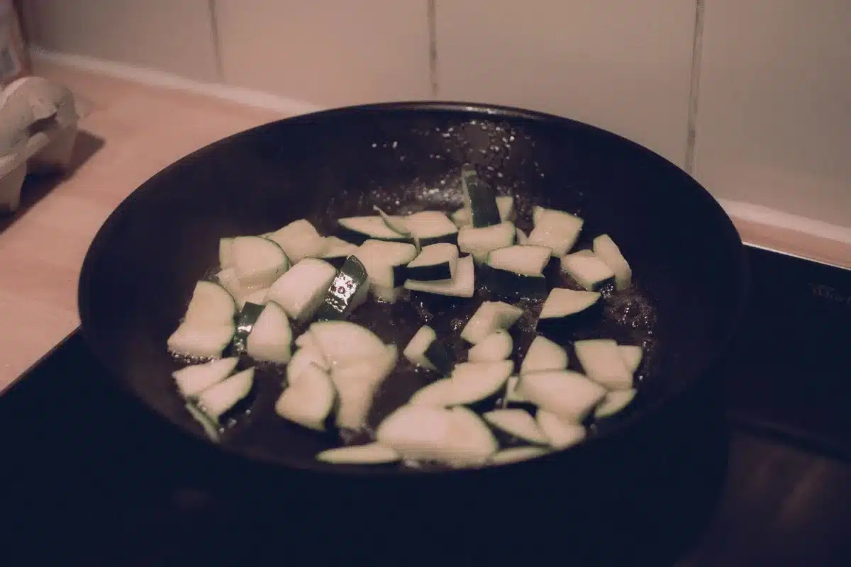 Galettes de courgettes dorées à la cuisson dans une poêle, croustillantes sur les deux faces