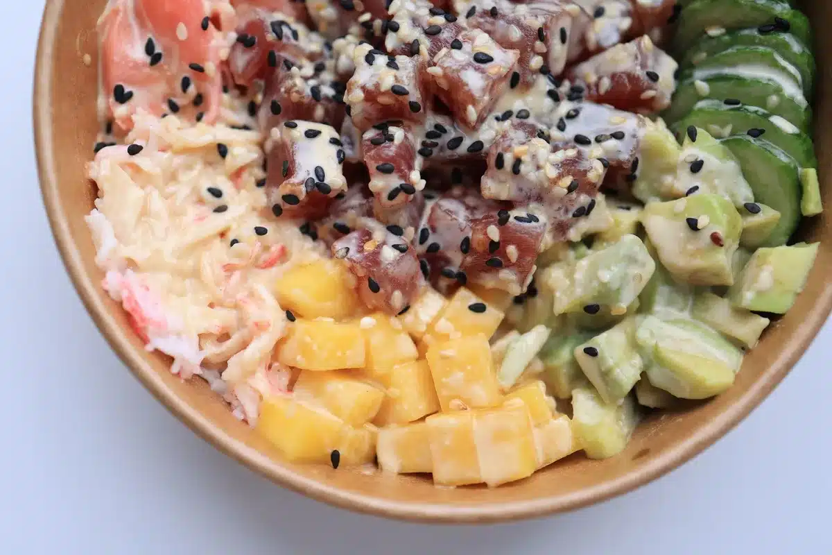 Ingr&eacute;dients pour sushi bowl: poisson cru, avocat, mangue, riz et accompagnements