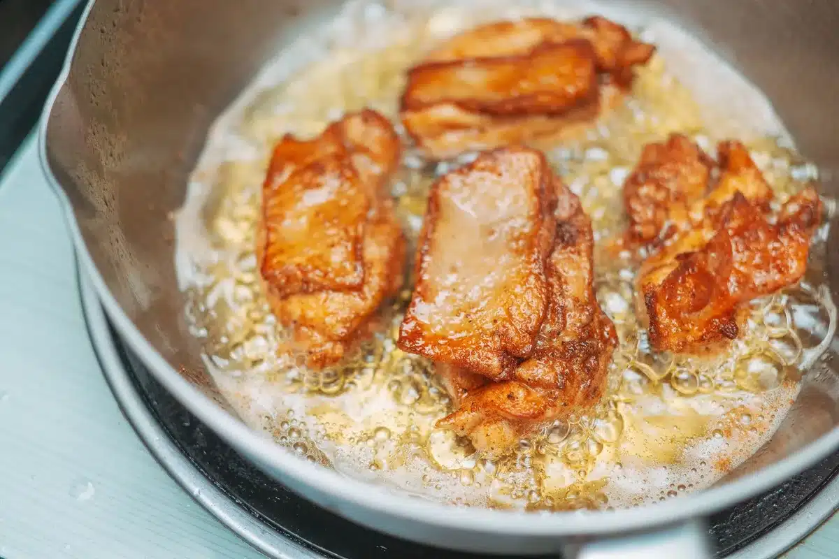 Poulet dorant dans une poêle chaude avec sauce tomate