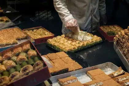 Mains garnissant des biscuits roulés croustillants avec une crème à la pistache sur un plan de travail