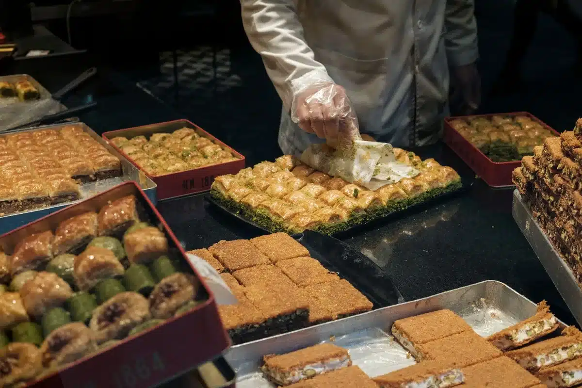 Mains garnissant des biscuits roulés croustillants avec une crème à la pistache sur un plan de travail