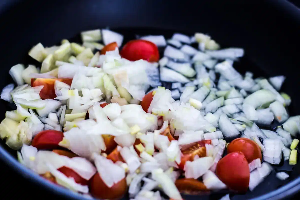 Mains préparant une tarte salée aux tomates et crème dans une cuisine ensoleillée