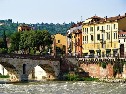 Passant vu de dos regardant des ruines romaines et un pont dans une place pavée à Vérone