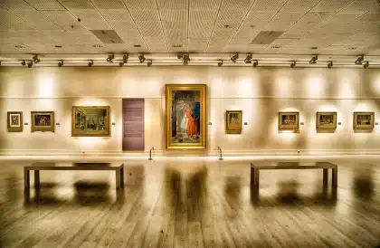 Grande salle lumineuse d'un musée avec visiteurs anonymes et œuvres accrochées