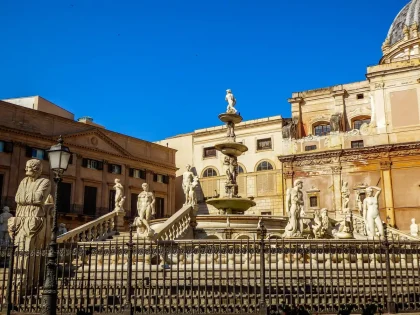Vue diurne d'une place historique avec fontaine baroque et visiteurs anonymes, files et kiosque