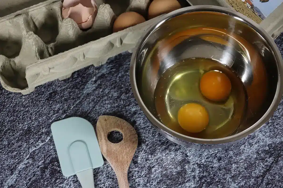 Mains mélangeant une pâte à muffin dans un cul-de-poule près d'une fenêtre