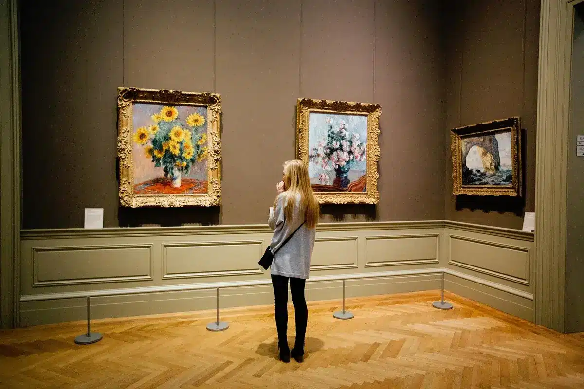 Salle d'exposition avec robes rouges et œuvres contemporaines exposées